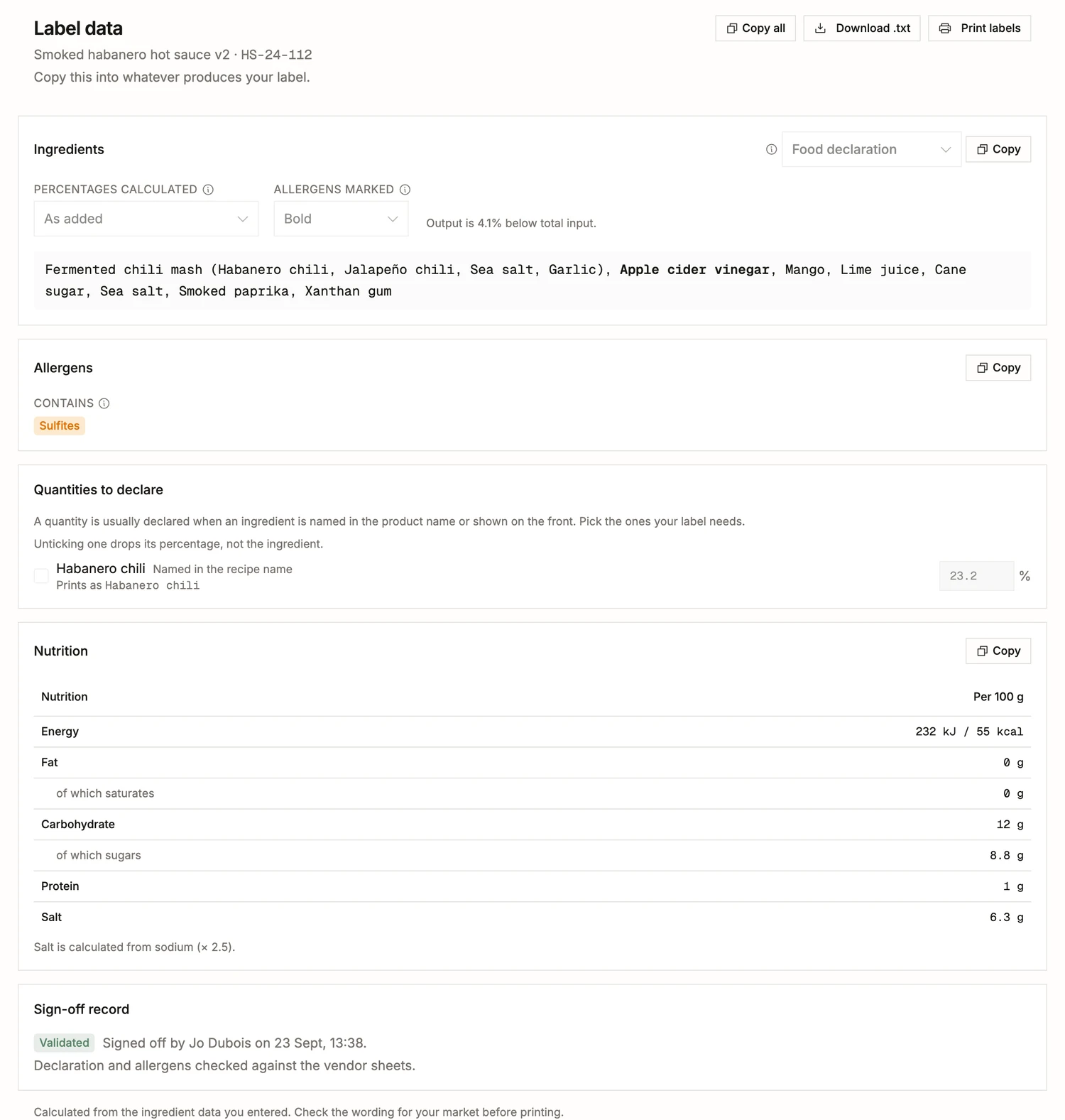The label data of a finished batch in BatchDash: lot HS-24-112’s ingredient list with the fermented chili mash broken out and the allergen in bold, a Contains line, the habanero’s share ready to declare, nutrition per 100 g with salt worked out from sodium, and the sign-off that validated them.