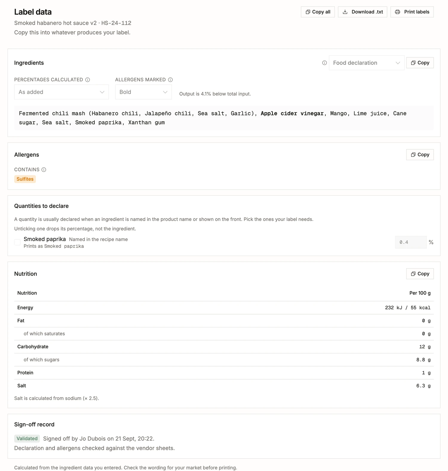The label data of a finished batch in BatchDash: the ingredient declaration with the fermented mash broken out and the allergen in bold, a Contains line, the quantity to declare for the smoked paprika, a nutrition panel per 100 g, and the sign-off that validated them.